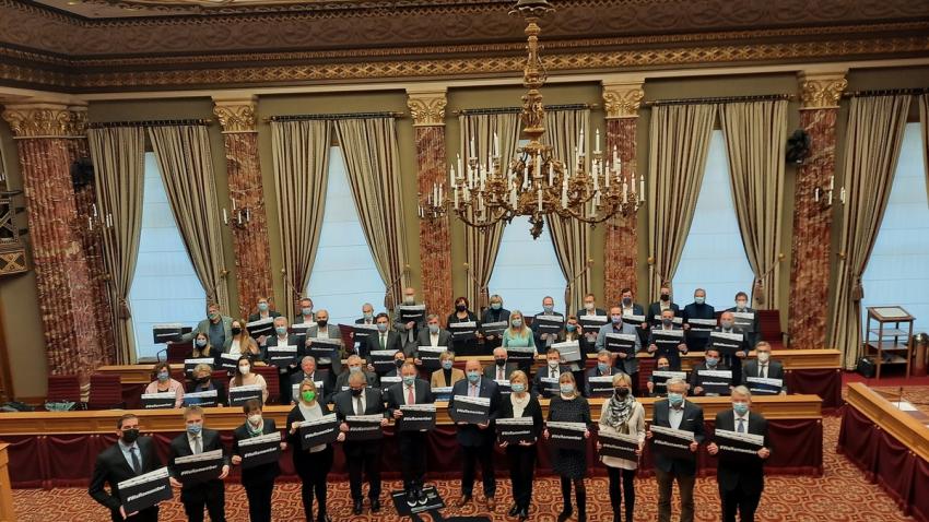 #WeRemember à la Chambre Les députés rassemblés en salle plénières tenant des pancartes #WeRemember
